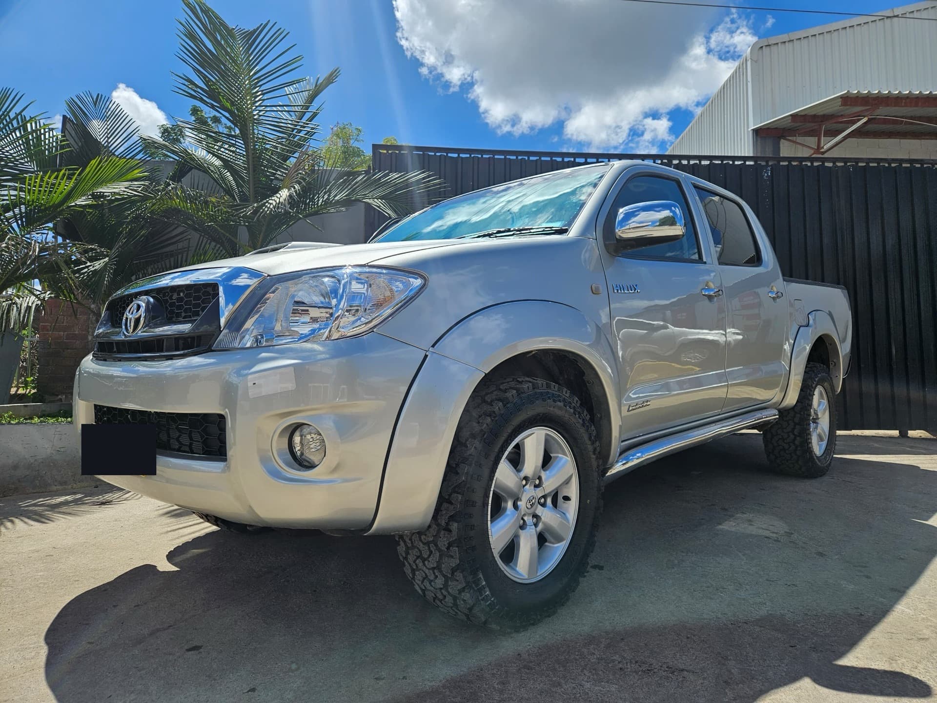 A silver Toyota Hilux rebuilt by Motor Madness, shot three-quarter front under a blue sky