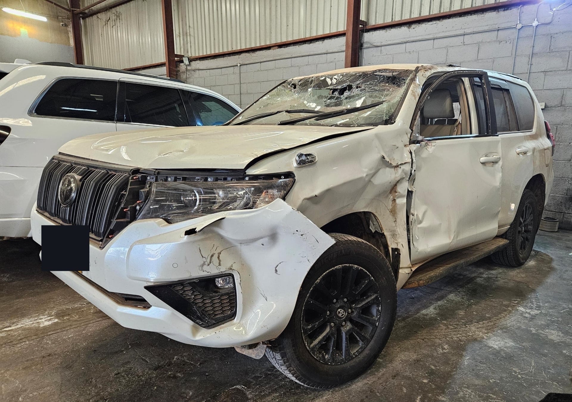 A white Toyota Prado written off in an accident, side crushed, before repair
